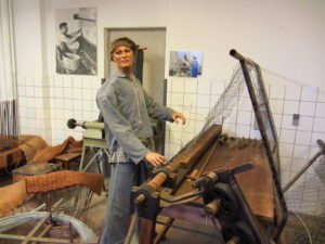 Photo 8: picture of mannequin. For patients deemed capable of work, Andersvænge had established several workshops. Women were predominantly occupied with textile work or in the gardens, while the men made fishing nets, worked in agriculture, the carpentry or the metal workshop.